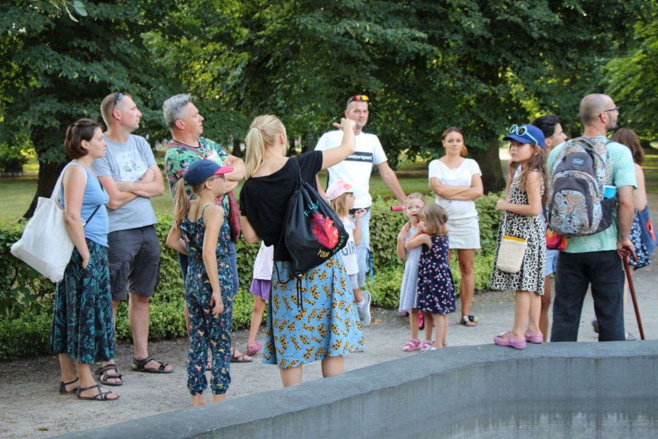 Grupa ludzi stoi przy betonowej fontannie