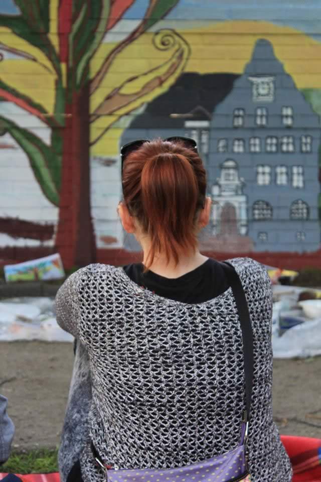 Siedząca tyłem dziewczyna patrzy na pomalowany mur